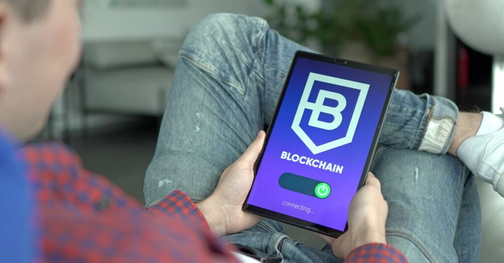 Erwachsener hält ein digitales Tablet, das eine Benutzeroberfläche einer Blockchain-Anwendung anzeigt.