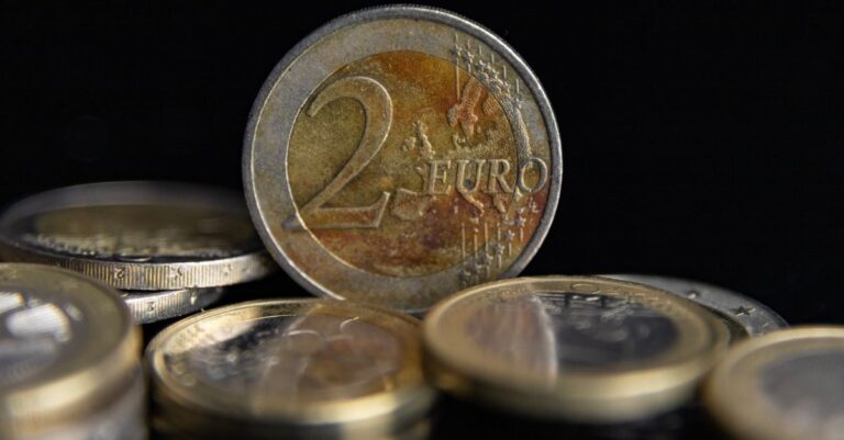 Detaillierte Makroaufnahme von Euro-Münzen, die vor einem schwarzen Hintergrund gestapelt sind.